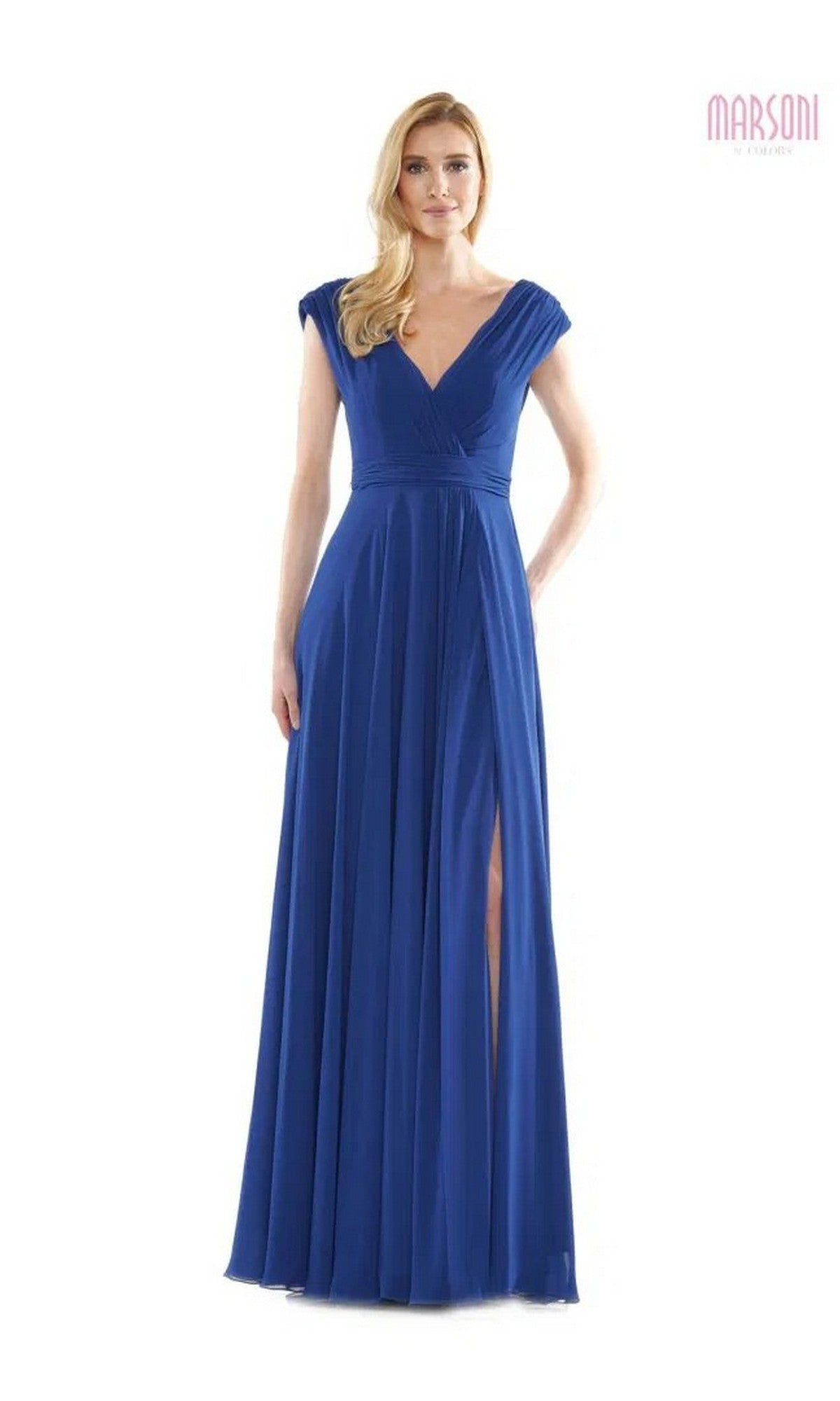 A woman wears the Marsoni M251 long formal dress in indigo blue, featuring cap sleeves, a V-neckline, pleated chiffon bodice, high slit, and floor-length skirt, standing against a plain white background.